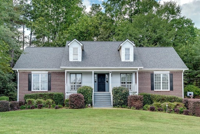 cape cod home with covered porch and a front lawn