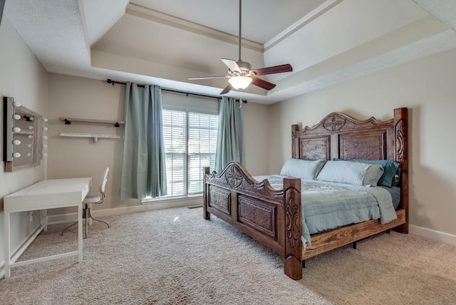 carpeted bedroom with ceiling fan, a raised ceiling, and ornamental molding