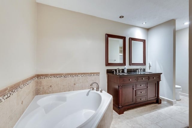 bathroom with tile patterned flooring, vanity, toilet, and tiled tub