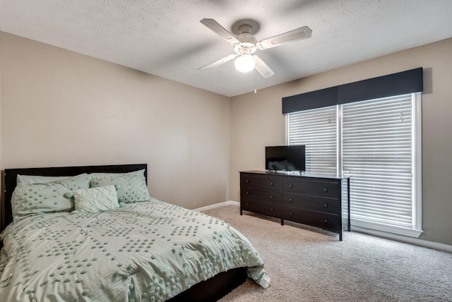 bedroom featuring a textured ceiling, light colored carpet, and ceiling fan