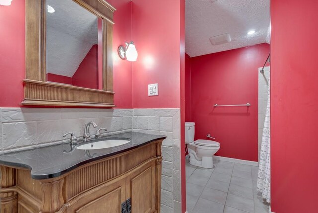 bathroom with tile patterned flooring, lofted ceiling, a textured ceiling, toilet, and vanity