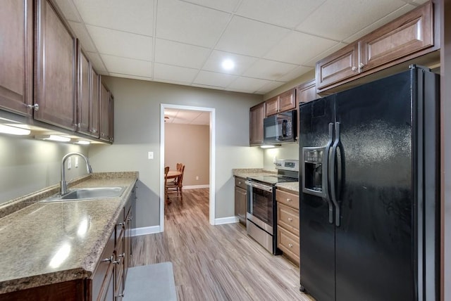 kitchen featuring black appliances, a paneled ceiling, light wood-type flooring, and sink