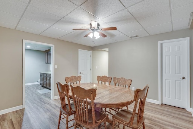 dining space featuring ceiling fan, a drop ceiling, and light wood-type flooring