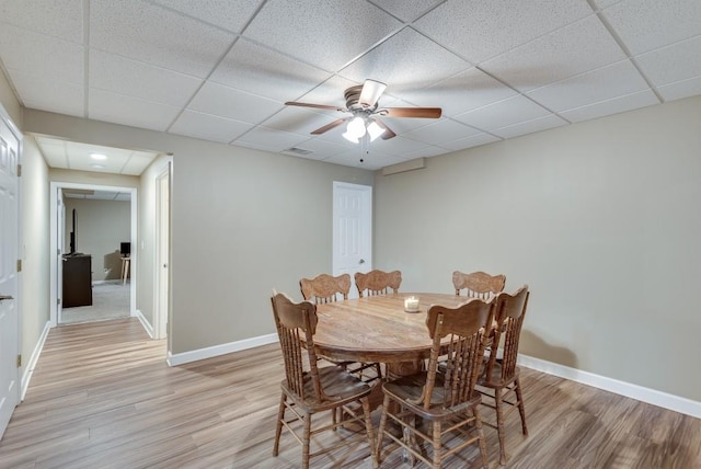 dining room with a paneled ceiling, ceiling fan, and light hardwood / wood-style flooring