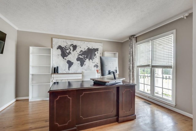 office area with a healthy amount of sunlight, a textured ceiling, and light wood-type flooring