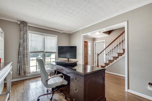 office space with ornamental molding, a textured ceiling, and light wood-type flooring