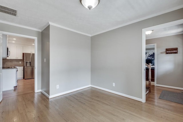 unfurnished room featuring a textured ceiling, light wood-type flooring, and ornamental molding