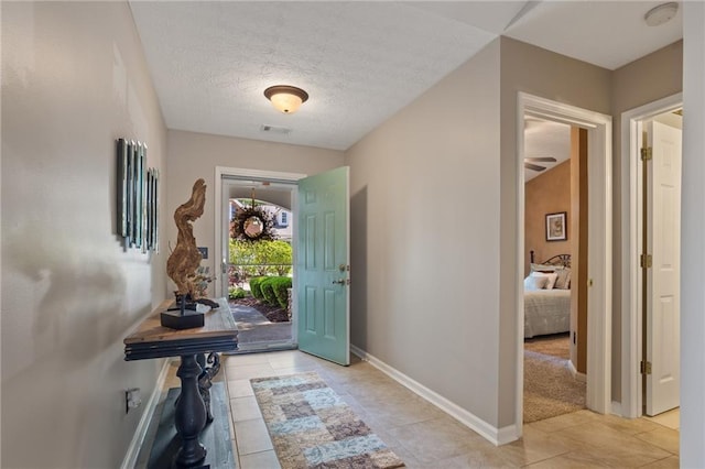 foyer entrance featuring a textured ceiling, visible vents, tile patterned floors, and baseboards