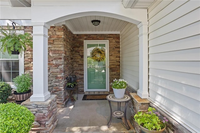 entrance to property featuring a porch and stone siding
