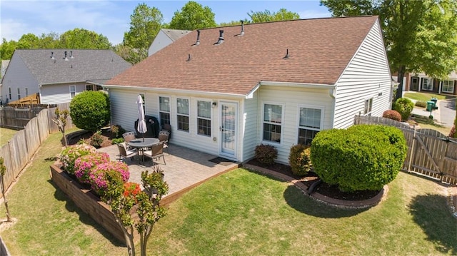 rear view of house featuring a lawn, a fenced backyard, roof with shingles, and a patio