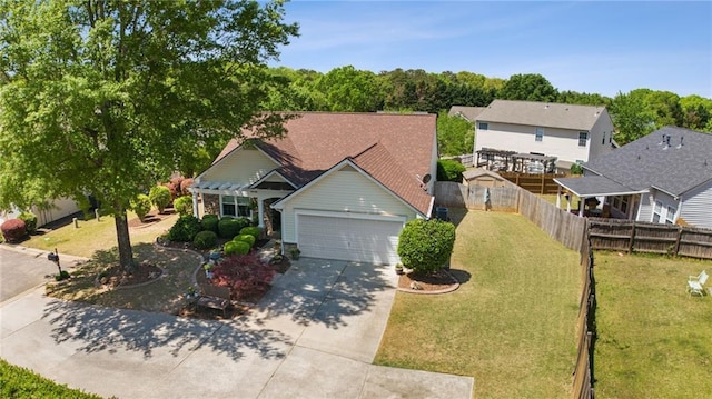 view of front of property featuring driveway, fence, a front yard, and a garage