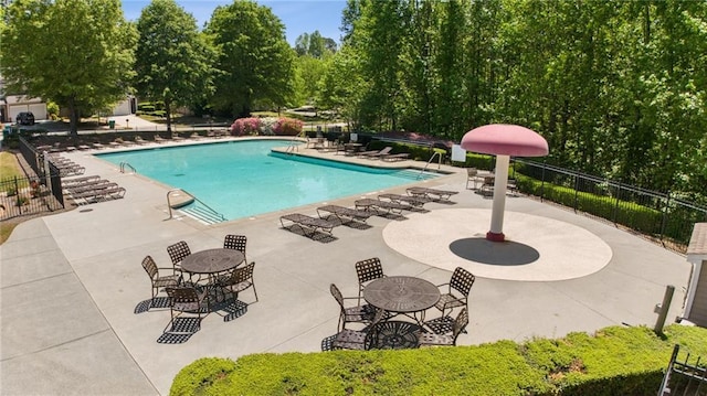 pool with a patio area and fence
