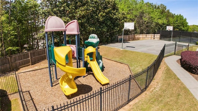 exterior space with community basketball court, fence, and a lawn