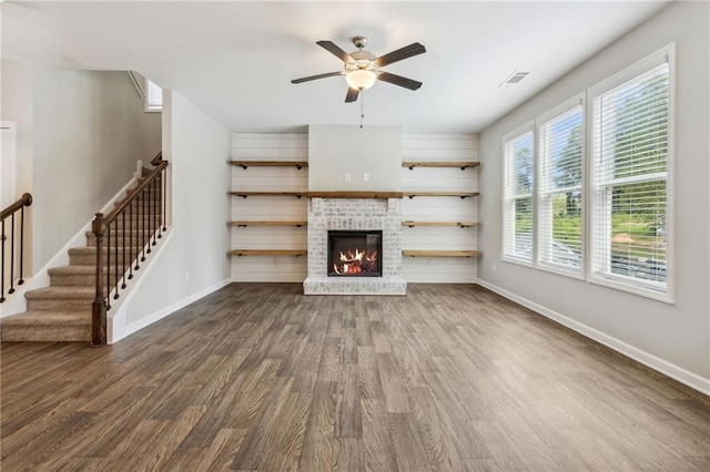 unfurnished living room with hardwood / wood-style floors, a brick fireplace, and ceiling fan