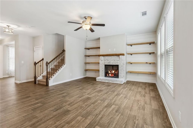 unfurnished living room with ceiling fan, a fireplace, and wood-type flooring