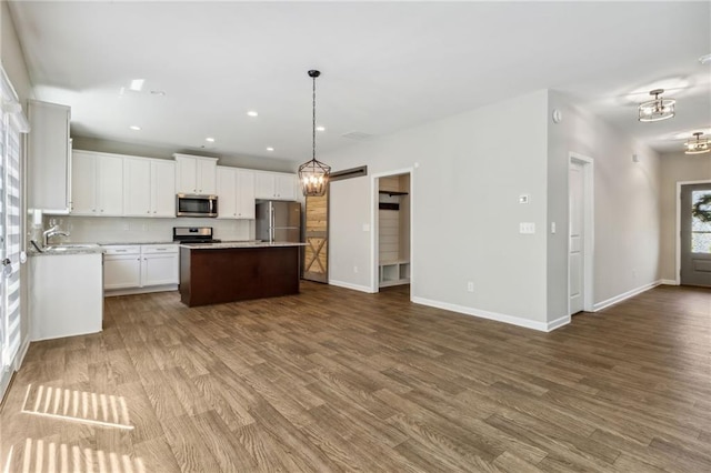 kitchen featuring appliances with stainless steel finishes, dark hardwood / wood-style flooring, decorative light fixtures, a center island, and white cabinetry