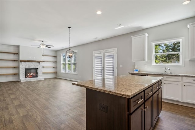 kitchen with white cabinetry, dark brown cabinets, decorative light fixtures, and a brick fireplace