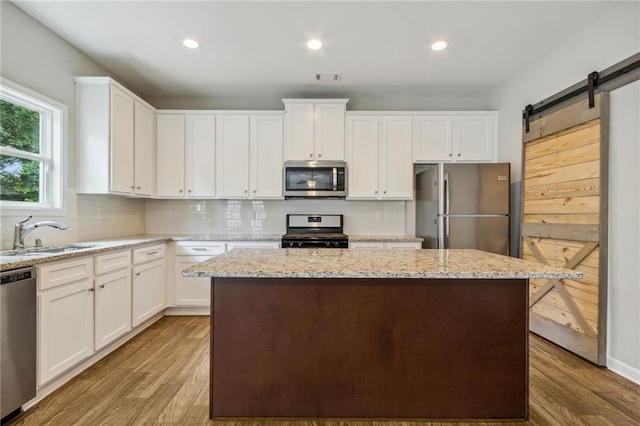 kitchen featuring a barn door, sink, white cabinetry, and stainless steel appliances