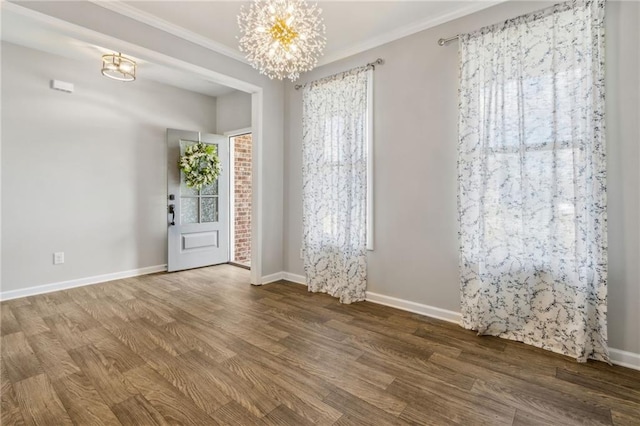 unfurnished room with hardwood / wood-style floors, plenty of natural light, crown molding, and an inviting chandelier