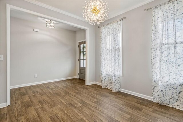 empty room with hardwood / wood-style flooring, an inviting chandelier, and crown molding