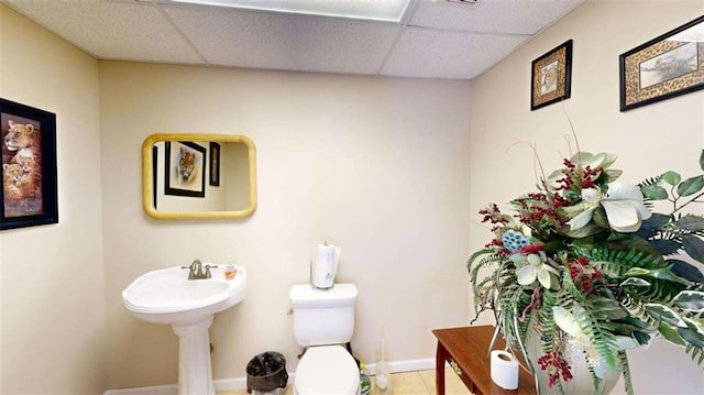 bathroom with a paneled ceiling, tile patterned floors, and toilet