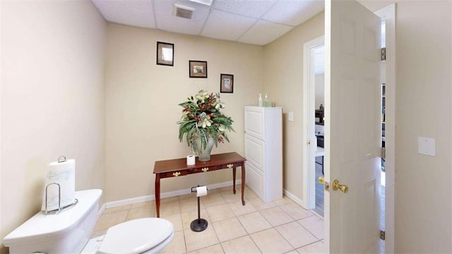 bathroom with tile patterned flooring, a paneled ceiling, and toilet