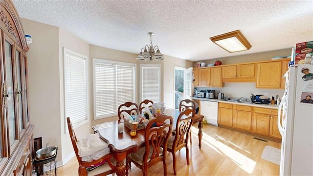 dining area featuring a textured ceiling, a notable chandelier, and light hardwood / wood-style floors