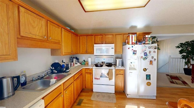 kitchen featuring white appliances, light hardwood / wood-style floors, and sink