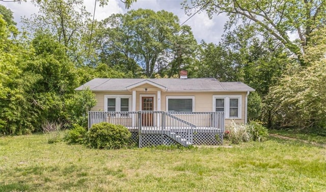bungalow-style house featuring a deck, a chimney, and a front yard