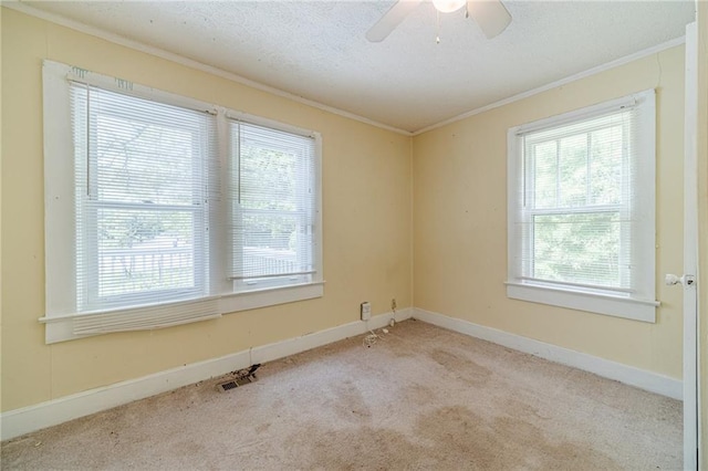 carpeted spare room with crown molding, a textured ceiling, ceiling fan, and visible vents