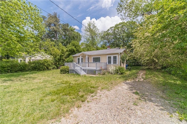 view of front of property with a chimney, a wooden deck, and a front yard