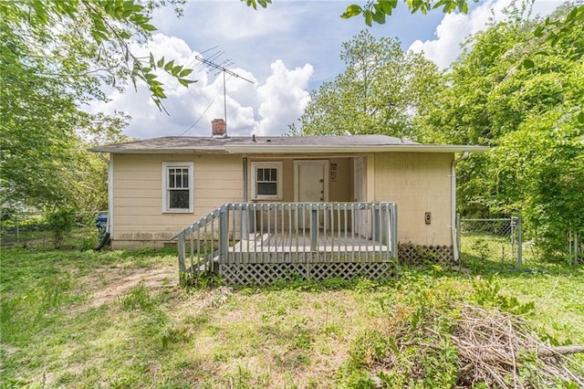 rear view of house featuring a wooden deck, a chimney, and fence