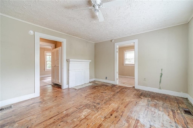 spare room featuring ceiling fan, ornamental molding, a textured ceiling, and visible vents