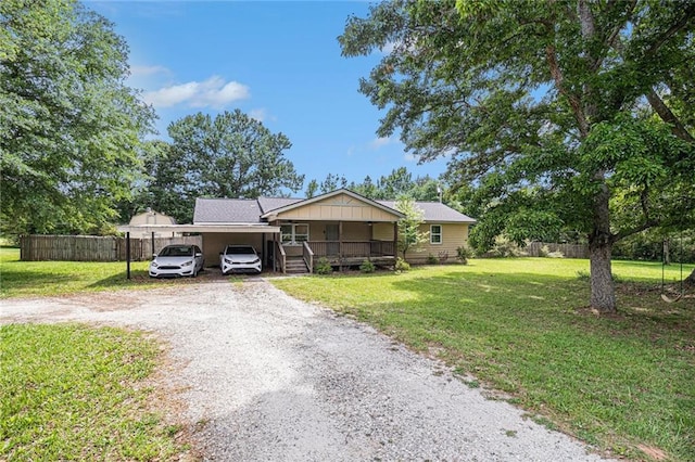 view of front facade featuring covered porch, an attached carport, fence, dirt driveway, and a front yard