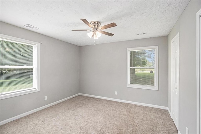 carpeted empty room featuring baseboards, a ceiling fan, and visible vents