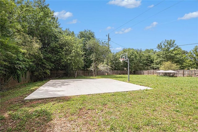 view of basketball court featuring a lawn and a fenced backyard