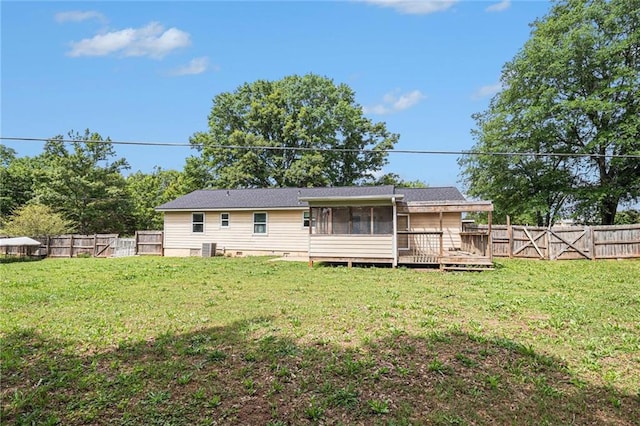 rear view of house with a fenced backyard, a sunroom, and a yard