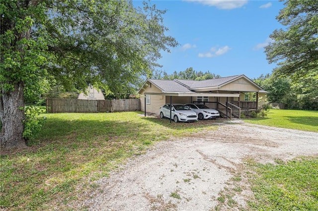 exterior space featuring fence, dirt driveway, and a lawn