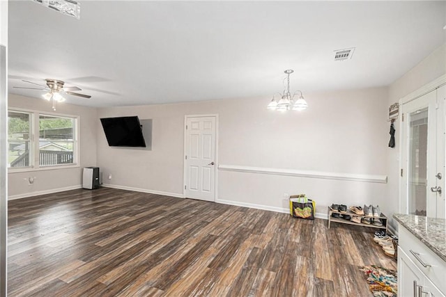 interior space with baseboards, dark wood finished floors, visible vents, and ceiling fan with notable chandelier