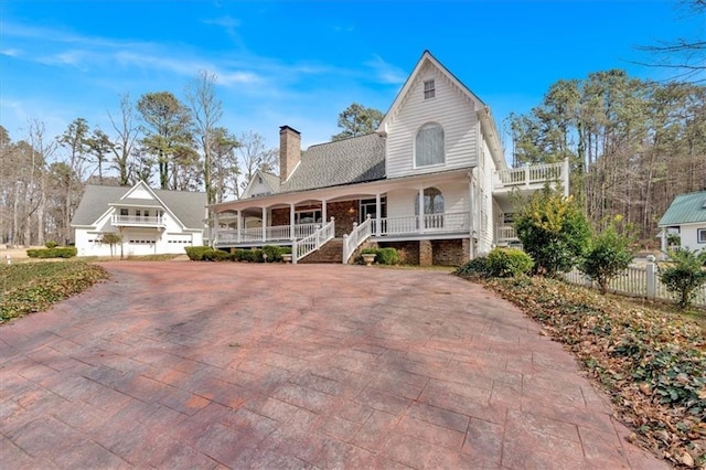 view of front facade with covered porch, decorative driveway, and a chimney