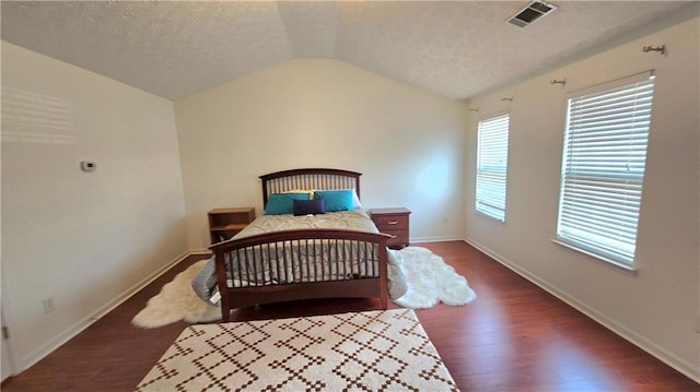 bedroom with visible vents, a textured ceiling, wood finished floors, baseboards, and vaulted ceiling