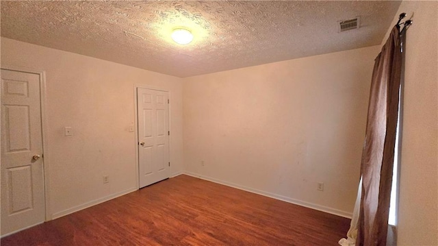 empty room with baseboards, wood finished floors, visible vents, and a textured ceiling