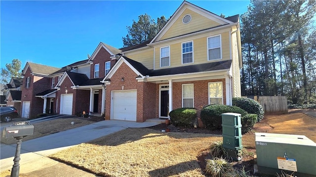 traditional-style house featuring a garage, brick siding, driveway, and fence