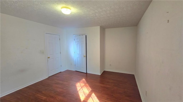 unfurnished bedroom featuring wood finished floors, baseboards, a closet, and a textured ceiling