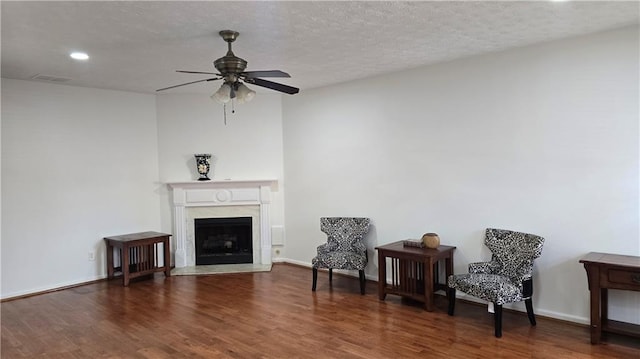 living area featuring a fireplace, wood finished floors, visible vents, and a textured ceiling