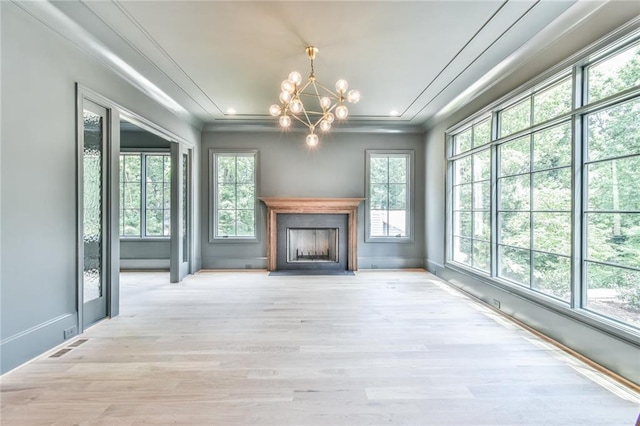 unfurnished living room featuring a notable chandelier, crown molding, and light hardwood / wood-style flooring