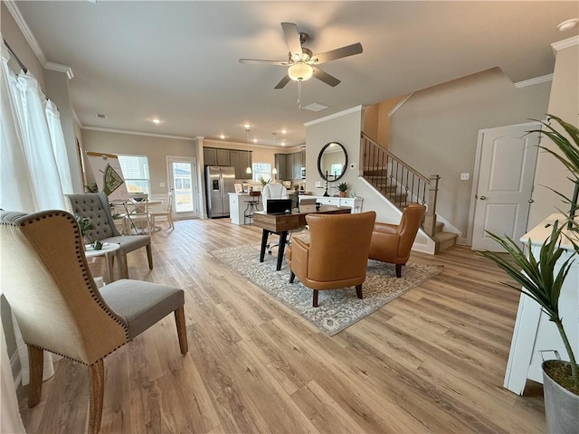 living room with crown molding, ceiling fan, and light wood-type flooring