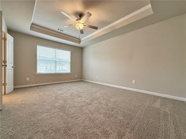 empty room featuring ceiling fan, ornamental molding, a raised ceiling, and carpet floors