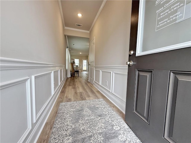 corridor featuring ornamental molding and light hardwood / wood-style floors