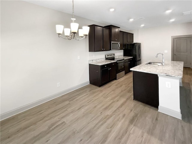 kitchen featuring a notable chandelier, light wood-style flooring, a sink, appliances with stainless steel finishes, and baseboards